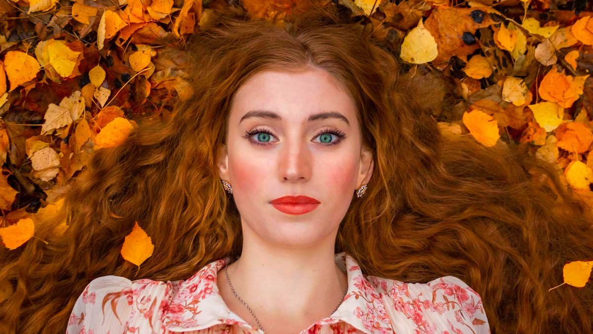 melhores bases de alta cobertura mulher ruiva com batom vermelho no meio de folhas no outono