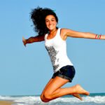 mulher pulando praia bronzeada